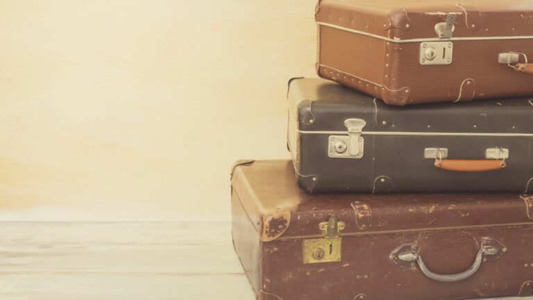 Kolme vanhaa matkalaukkua pinossa